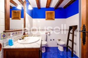 a blue and white bathroom with a toilet and a sink at Casa rural La antigua botiga in La Iglesuela del Cid