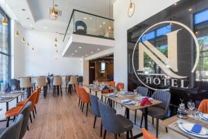 a restaurant with tables and chairs and a large sign on the wall at N Hotel in Sutomore