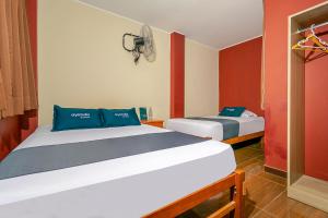 dwa łóżka w pokoju z czerwonym i białym w obiekcie Ayenda Muñoz w mieście Ica