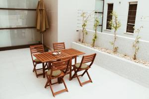 a wooden table with four chairs and an umbrella at Cozy seaside apartment with pool & terrace in Split