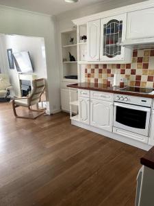 a kitchen with white cabinets and a wooden floor at Burlington Cottage - Ulverston, Lake District. in Ulverston