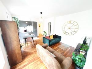 a living room with a couch and a clock on the wall at Home Sweet Home Ordener Marcadet in Paris