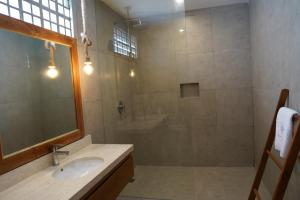 a bathroom with a shower and a sink and a mirror at Umah Anyar in Canggu