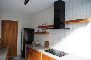 een keuken met een wastafel en een zwarte koelkast bij Umah Anyar in Canggu