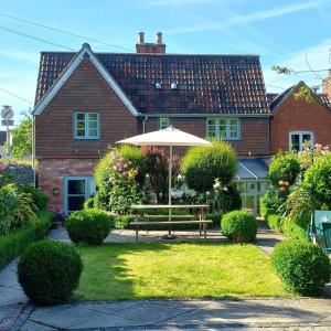 a house with a bench and an umbrella in the yard at Parsnips House BnB Glastonbury in Glastonbury