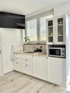 una cucina bianca con lavandino e forno a microonde di P&P APARTMÁNY Bojnice a Bojnice