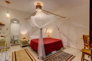 a bedroom with a red bed with a white canopy at Pousada Ilha Verde in Itacaré