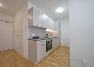 Il comprend une cuisine avec des placards blancs et du parquet. dans l'établissement Meraki Apartment, à Vienne