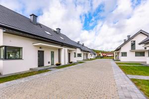 a row of white houses with a driveway at Osada Nord domki wypoczynkowe in Jastrzębia Góra