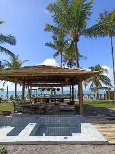 um pavilhão de madeira com uma mesa de piquenique e palmeiras em Nuhatê Casa Hotel em Caraíva