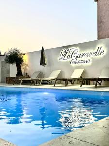 une piscine avec des chaises et un panneau sur un mur dans l'établissement Hôtel Restaurant La Caravelle, à Sari-Solenzara