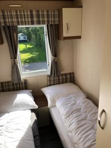 2 Betten in einem kleinen Zimmer mit Fenster in der Unterkunft Ferienhaus Nr916 Persdirekt am Wattenmeer mit Meerblick, hundefreundlich eingezäunt in Westerland