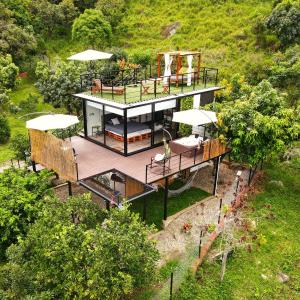 a house with a deck with umbrellas on a hill at Oasis Glamping Tena Cundinamarca Cerca a Bogotá in Tena