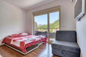 a bedroom with a bed and a window and a chair at Apartmani Čukić Rafailovići in Budva
