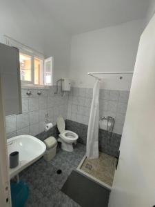 La salle de bains est pourvue de toilettes, d'un lavabo et d'une douche. dans l'établissement NAFSIKA Apartments, à Agios Georgios Pagon