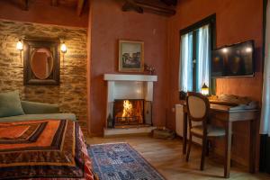 a bedroom with a fireplace and a bed and a desk at Archontiko Stamou in Zagora
