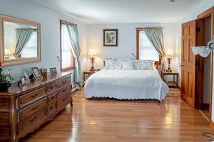 a bedroom with a bed and a dresser and two windows at Pet-Friendly West Yarmouth Home, Half Mi to Beach! in West Yarmouth