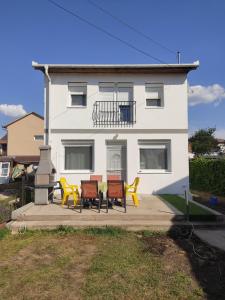 a house with three chairs and a table in front of it at Nurmi House in Hajdúszoboszló