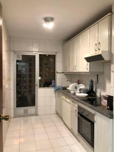 a white kitchen with a sink and a stove at Be like at home New York in Alcalá de Henares