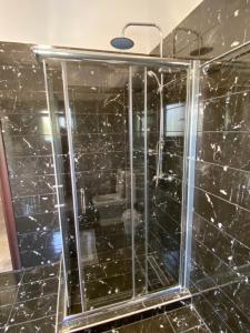a glass shower in a bathroom with black tiles at Villa Gloria Plataria in Igoumenitsa +22 photos