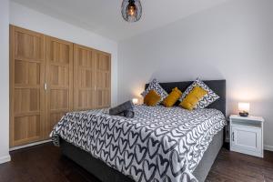 a bedroom with a black and white bed with yellow pillows at King Size Bed - Free Private Parking - Garden & Terrace - 14min from DisneyLand in Ferrières-en-Brie