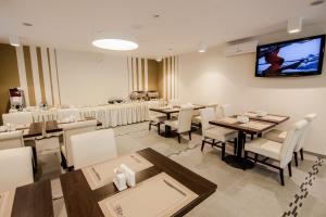 a dining room with tables and chairs and a flat screen tv at Optima Rivne in Rivne