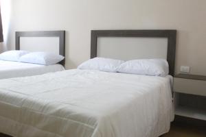 2 Betten in einem Schlafzimmer mit weißer Bettwäsche und Kissen in der Unterkunft Hotel Casa Hidalgo in Torreón