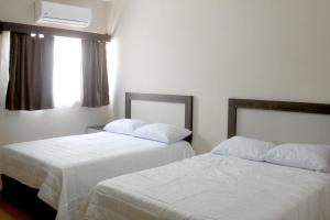 2 Betten in einem Hotelzimmer mit weißer Bettwäsche in der Unterkunft Hotel Casa Hidalgo in Torreón