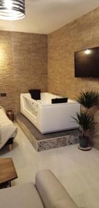 una gran bañera blanca en una habitación con sofá en ESTUDIO Jacuzzi SOL De JEREZ, en Jerez de la Frontera