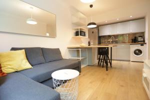 a living room with a blue couch and a kitchen at Sunrise Sopot Apartments in Sopot