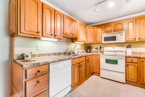 a kitchen with wooden cabinets and white appliances at Skyleaf Retreat in Sugar Mountain +17 photos