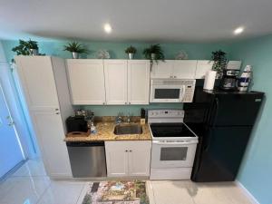 een keuken met witte kasten en een zwarte koelkast bij Luxury Zin Star - Studio in Fort Lauderdale