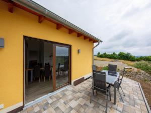 a yellow house with a patio with a table and chairs at Tranquil Holiday Home in Filz in the Eifel with Garden in Filz