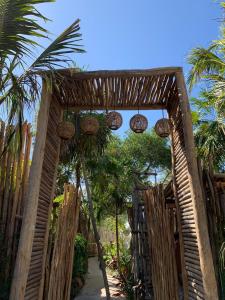 an entrance to a garden with a wooden gate and palm trees at Chiibal in Tulum