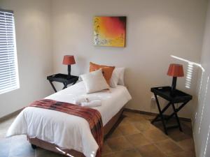 a bedroom with a bed with two lamps on tables at Airport Lodge Guest House in Kempton Park