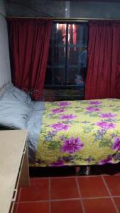 a bed with a colorful blanket on it in a room at Posada Lu.Lu in Choachí