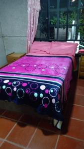 ein Bett mit einer lila Decke darüber in der Unterkunft Posada Lu.Lu in Choachí