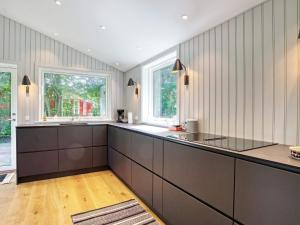 uma cozinha com armários castanhos e duas janelas em Holiday home Gilleleje LXXXIII em Gilleleje