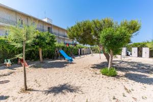 un parco giochi con alberi nella sabbia di fronte a un edificio di Appartamento Potì sulla spiaggia a Porto Cesareo