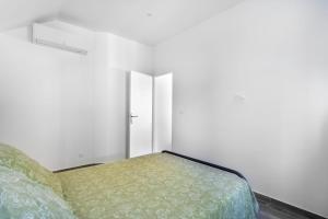 - une chambre avec un lit et un mur blanc dans l'établissement Luxurious 1 bedroom, AC, terrace, close beaches - Dodo et Tartine, à Carqueiranne