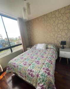 1 dormitorio con 1 cama con colcha de flores en Departamento completo en Miraflores Surquillo, en Lima