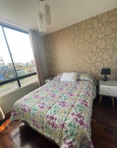 Un dormitorio con una cama con una colcha floral. en Departamento completo en Miraflores Surquillo, en Lima