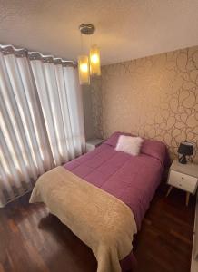 Un dormitorio con una cama con una manta morada. en Departamento completo en Miraflores Surquillo, en Lima