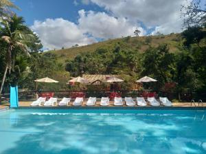 a pool with chairs and umbrellas next to a mountain at Sarandy Hotel Eco Parque in Paraíba do Sul +33 photos