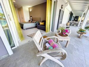 eine Veranda mit Stühlen und einem Bett sowie ein Schlafzimmer in der Unterkunft Frangipani Room in shared Villa Diamant, swimming pool, sea view in Grand Case