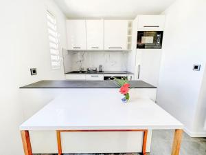cocina blanca con encimera blanca y mesa en Studio Aloe in shared Villa Diamant, infinity pool, sea view, en Grand Case