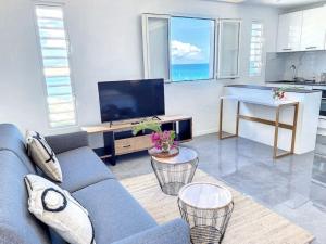 sala de estar con sofá azul y TV en Studio Aloe in shared Villa Diamant, infinity pool, sea view en Grand Case