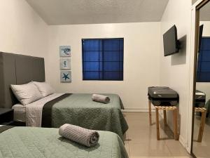 a bedroom with two beds and a flat screen tv at Bonanza Casa de Huespedes in Ciudad Juárez