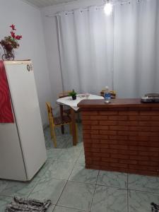 a kitchen with a table and a white refrigerator at Kitnet Recanto de Campos-Pertinho do Centro in Campos do Jordão