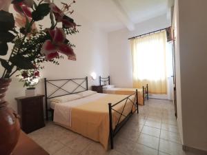 1 dormitorio con 2 camas y un jarrón con flores en Fattoria della Sabatina, en La Sabatina